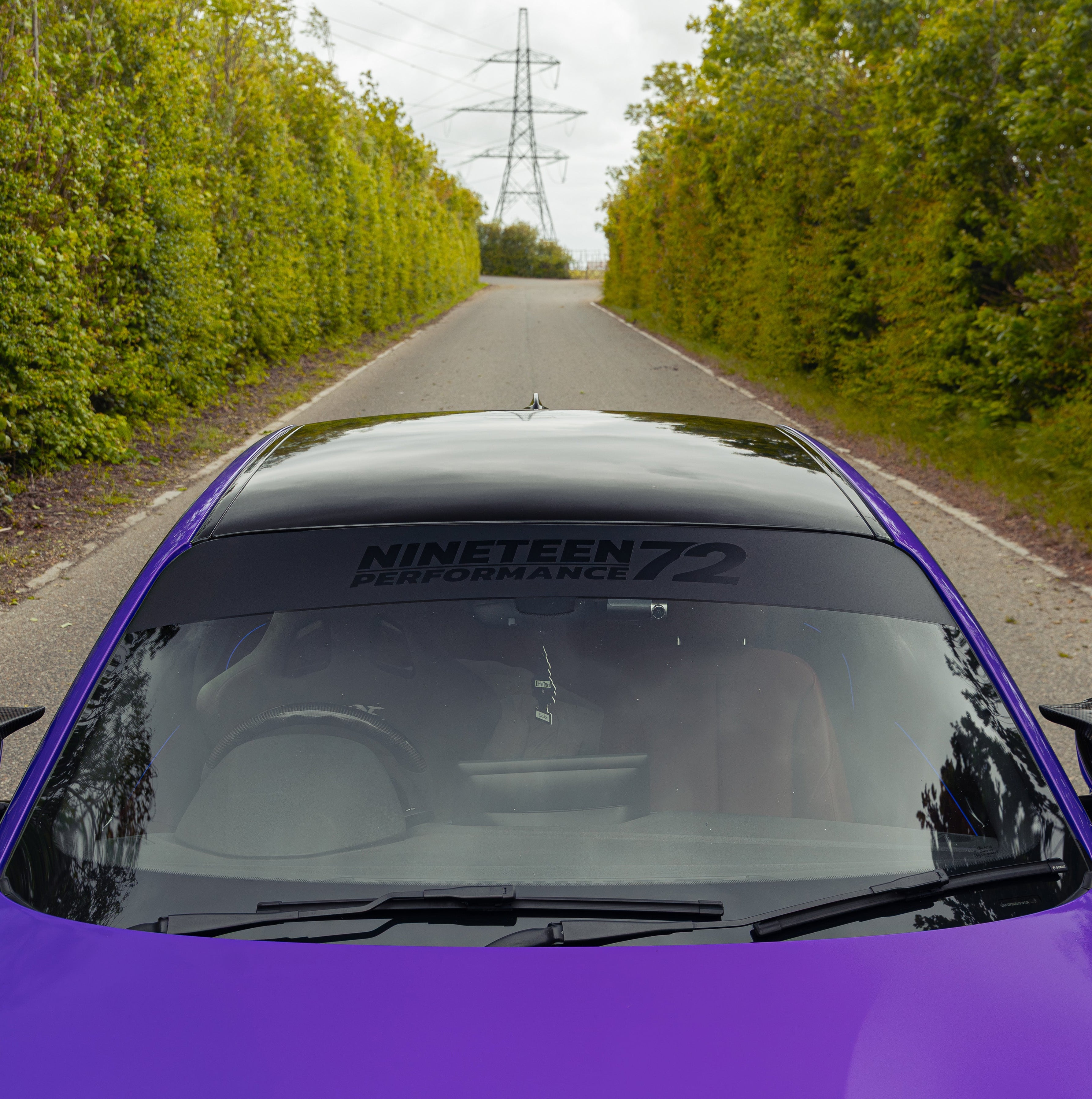 Nineteen72 Performance matte sunstrip with gloss black logo on a vehicle window for sporty style and sun protection.