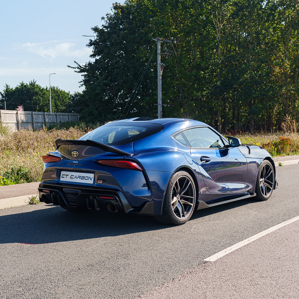 Carbon fiber diffuser add-on for Toyota Supra 2019+ A90 by CT Carbon, showing sleek, textured diffuser part on the vehicle.