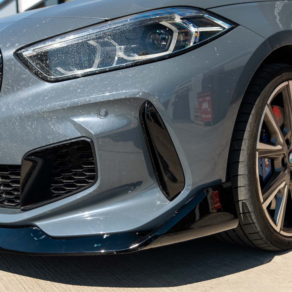 BMW F40 1 Series gloss black splitter by CT Carbon, showing the sleek front splitter with a V1 style design and glossy finish.