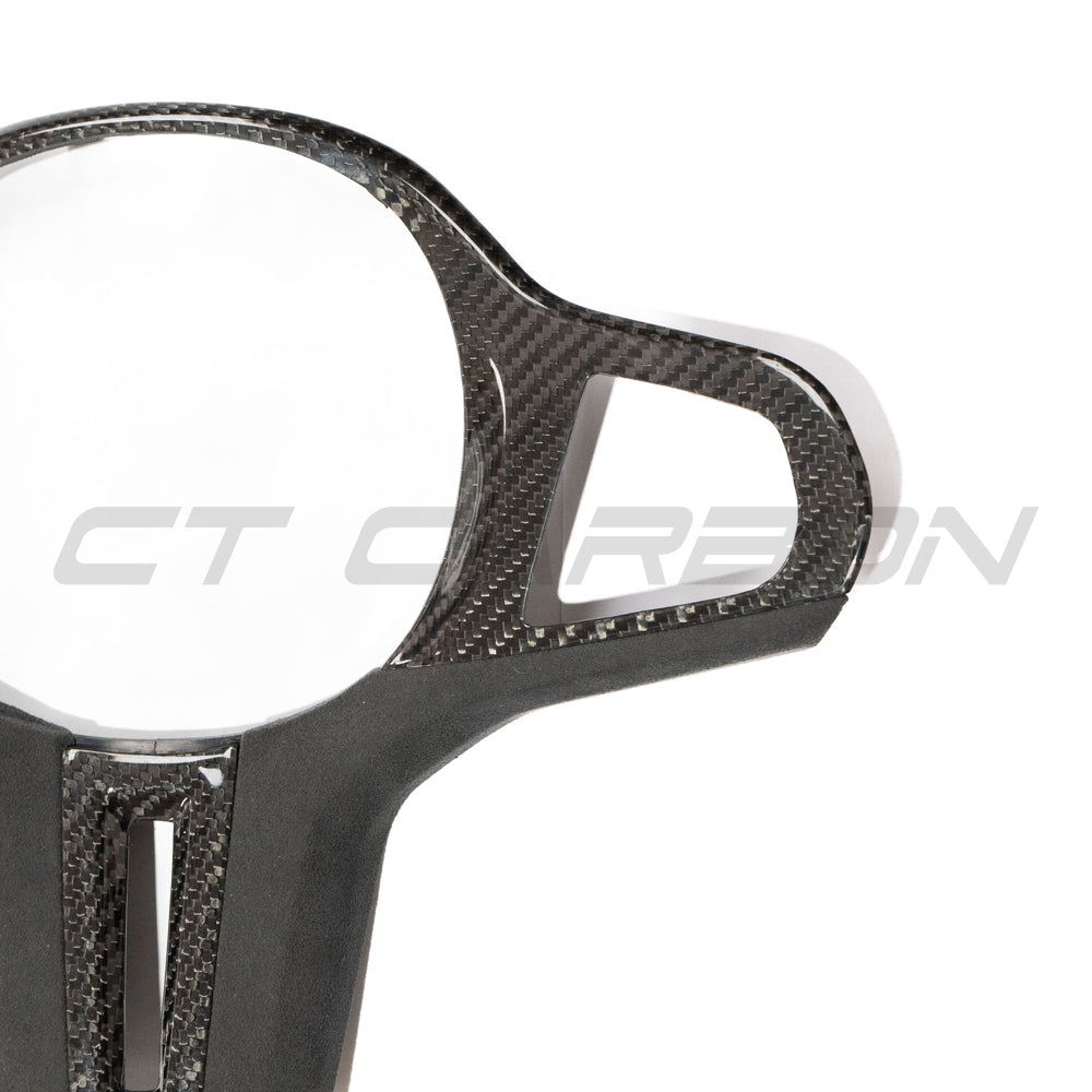 BMW Gxx M carbon fiber steering wheel trim by CT Carbon, close-up view of sleek, textured carbon fiber accessory for interior upgrade.