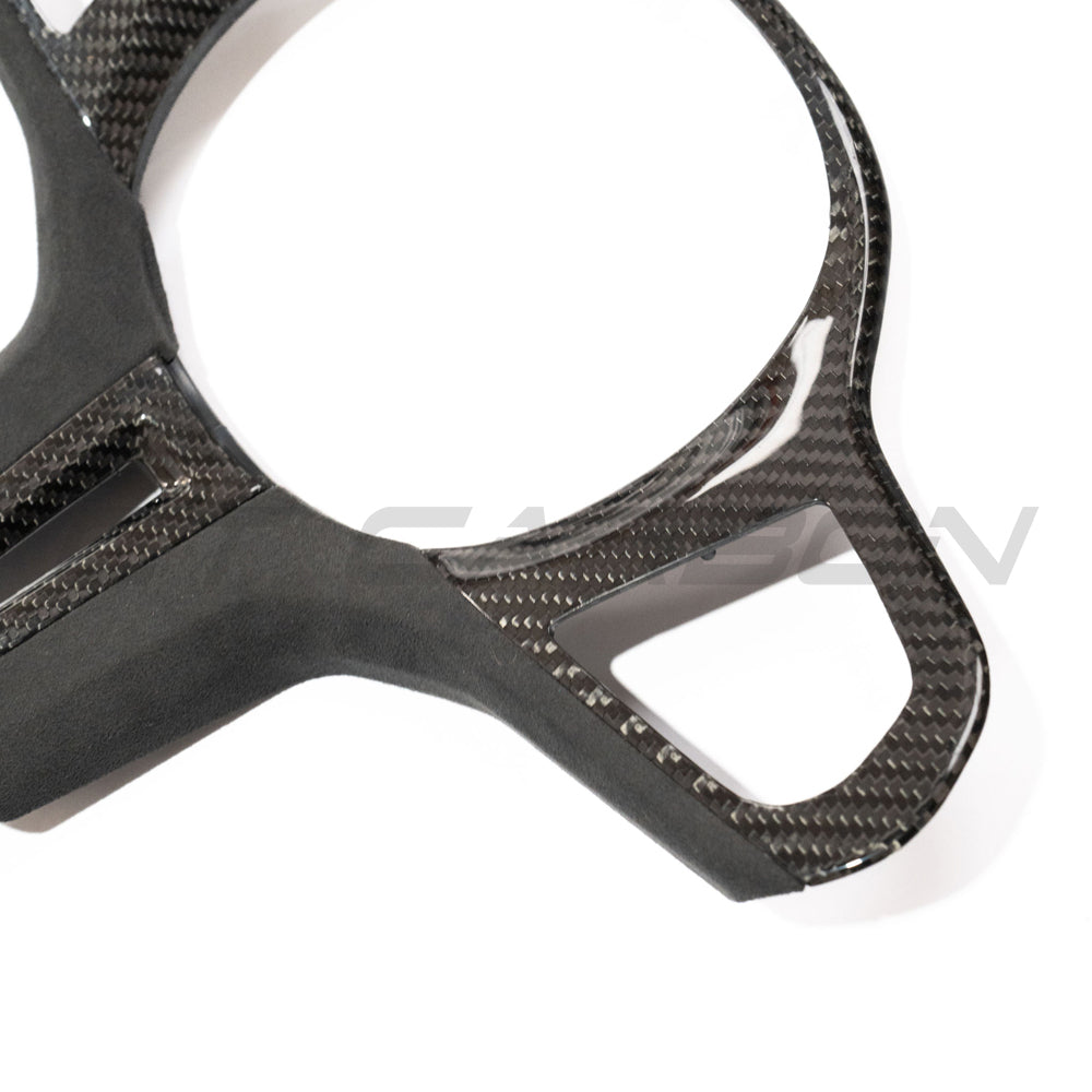 BMW Gxx M carbon fiber steering wheel trim accessory by CT Carbon, close-up of sleek black carbon fiber finish on steering wheel.