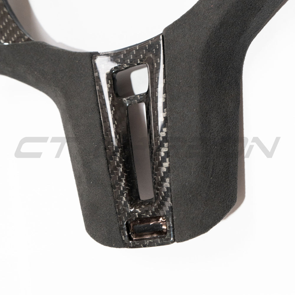 BMW Gxx M carbon fiber steering wheel trim with heating feature, crafted by CT Carbon, shown on a sporty vehicle interior.