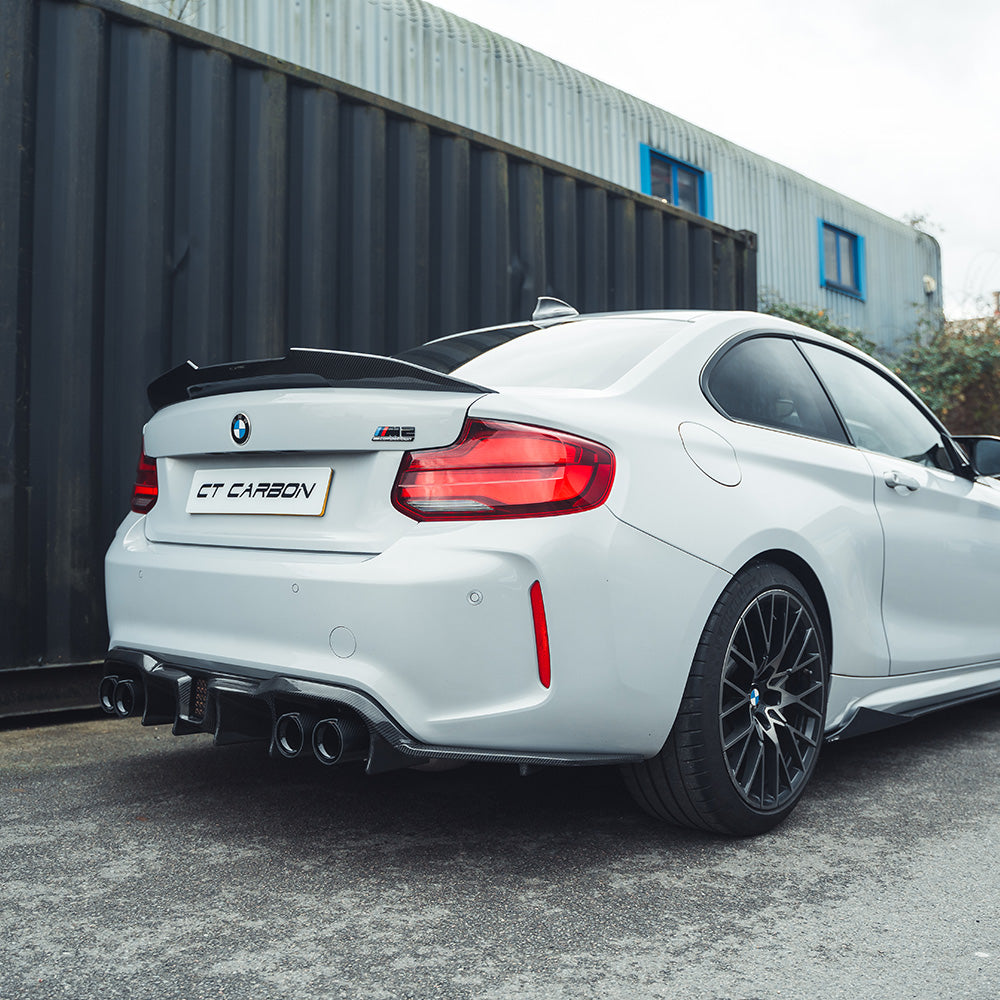 BMW M2 F87 carbon fibre diffuser by CT Carbon, featuring an aggressive V6 design, shown on a sleek sports car.