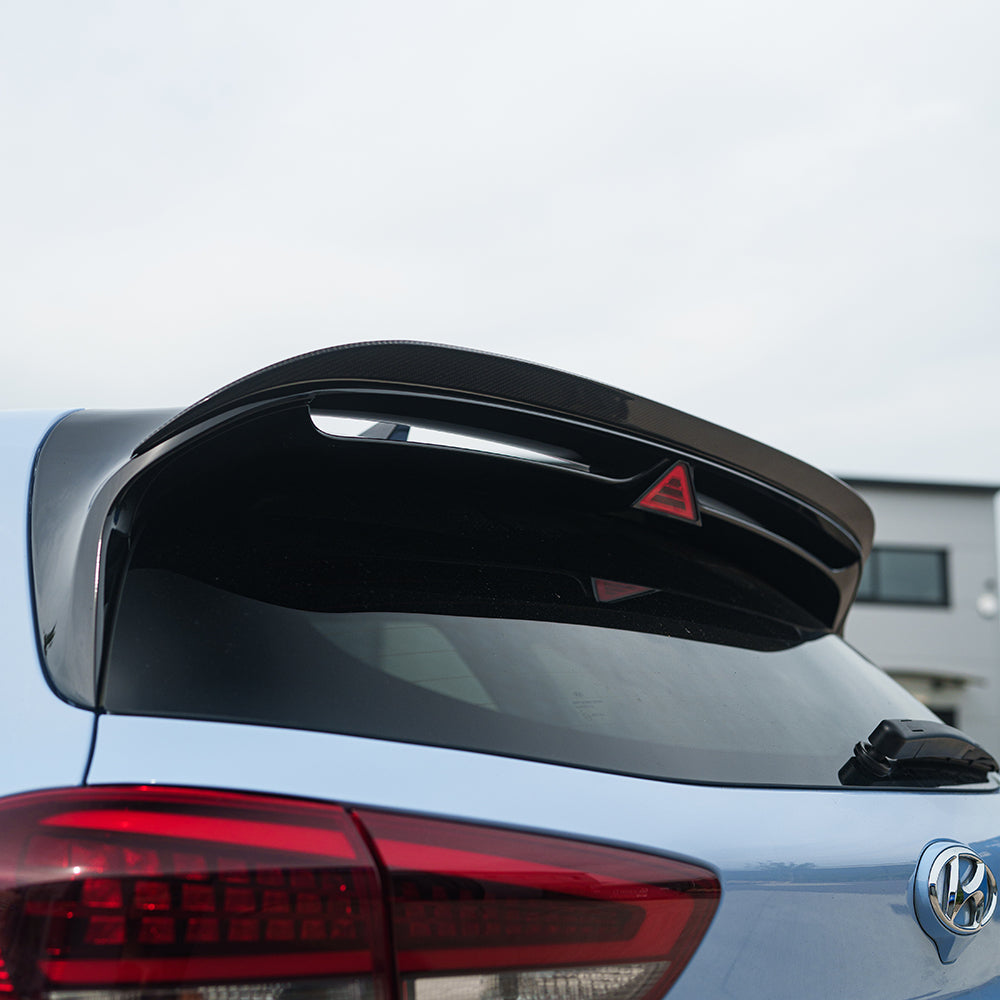 Hyundai i30N carbon fibre spoiler by CT Carbon, showing sleek aerodynamic design and glossy black finish on a white vehicle.