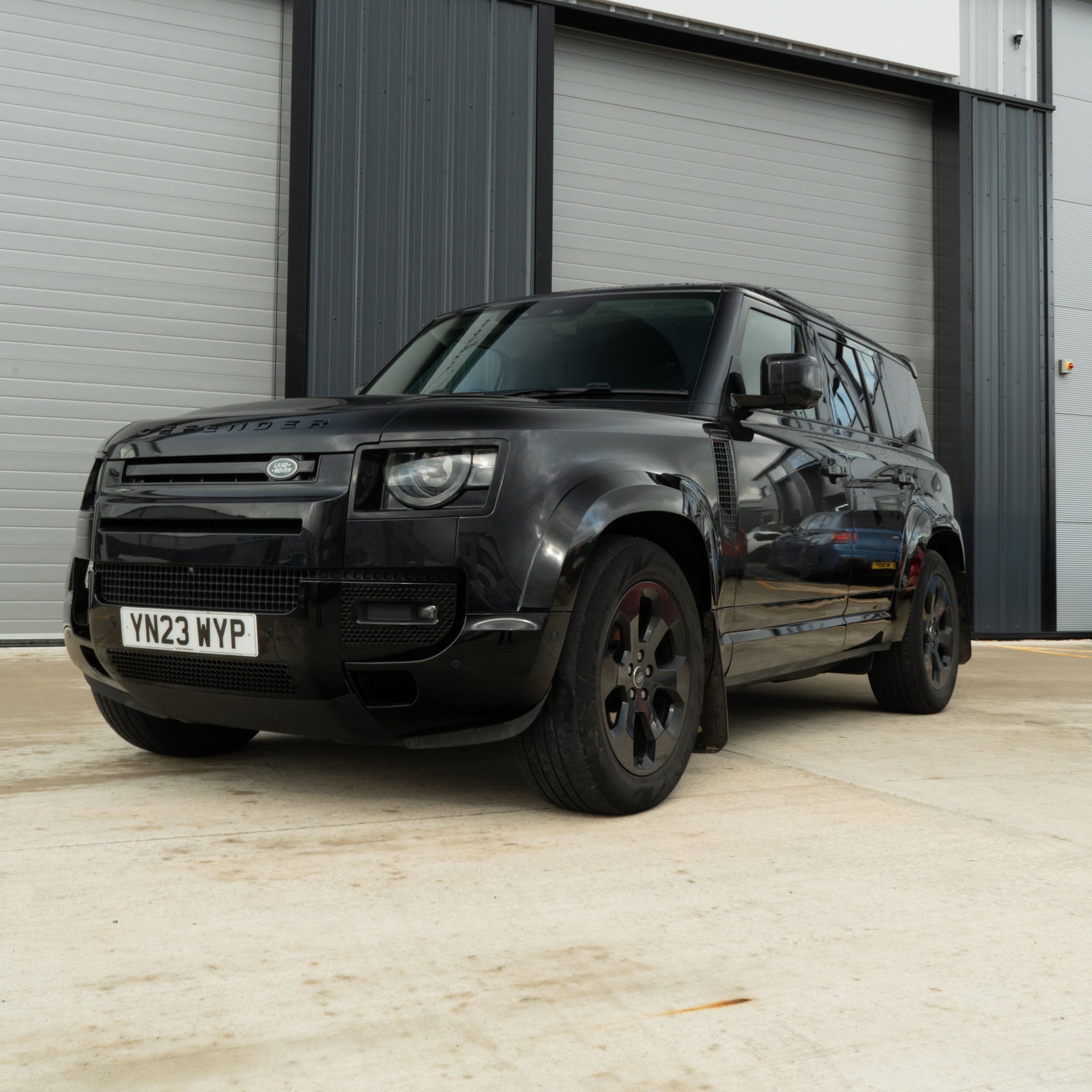 CT Carbon gloss black bumper corners for Land Rover Defender L663 90/110 front and rear, shown on vehicle in close-up image.