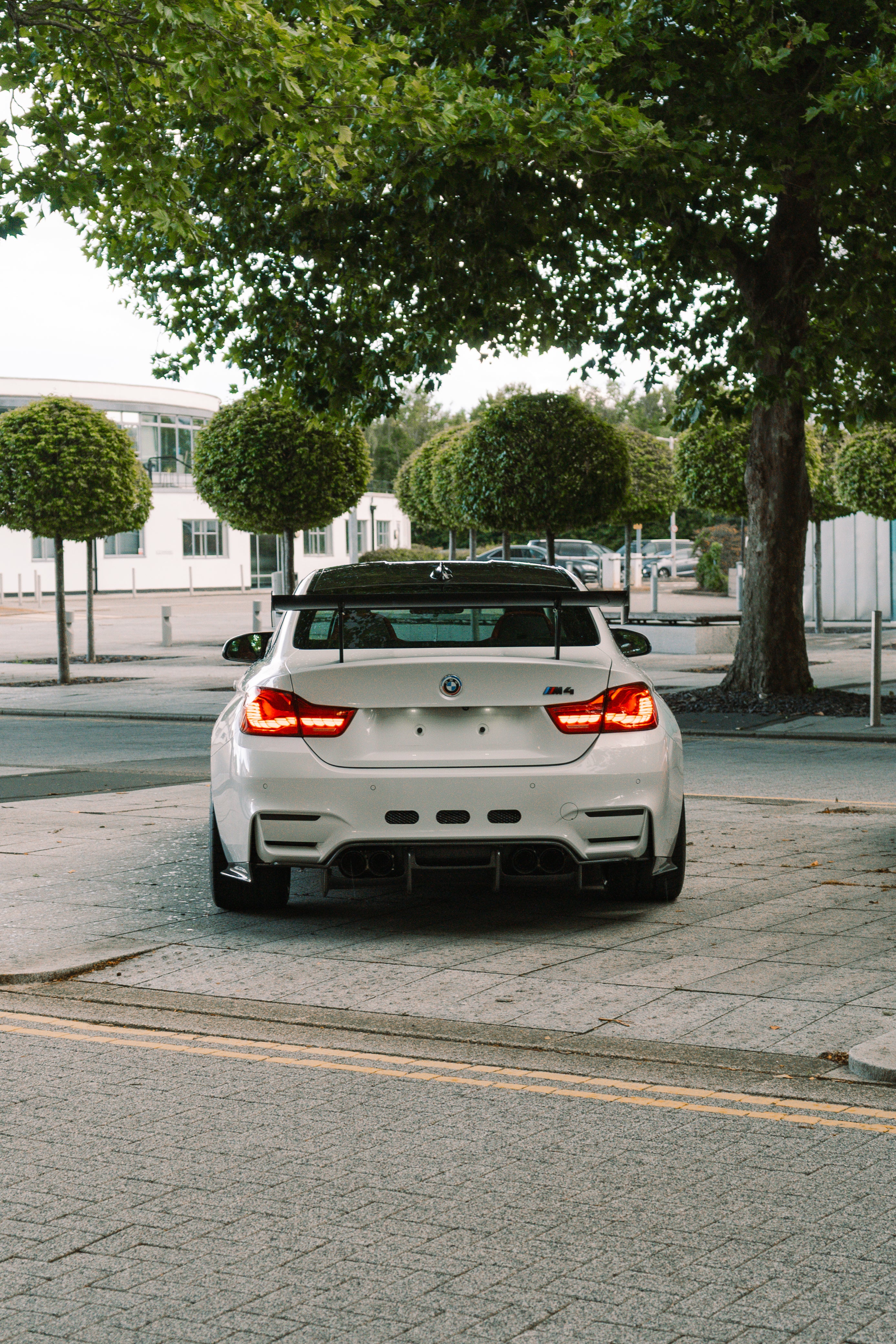 White BMW car parked on a street with trees and buildings in the background