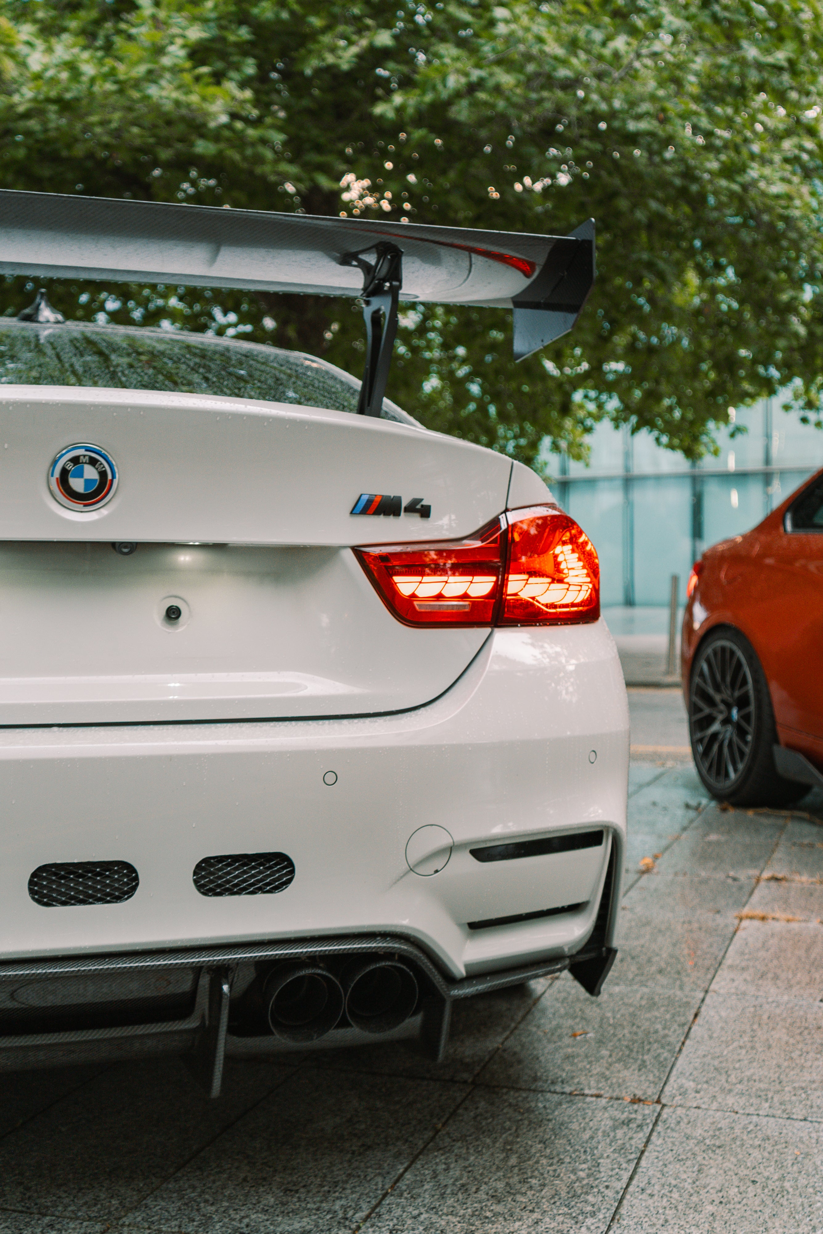 White BMW M4 with a large rear wing parked on a street.