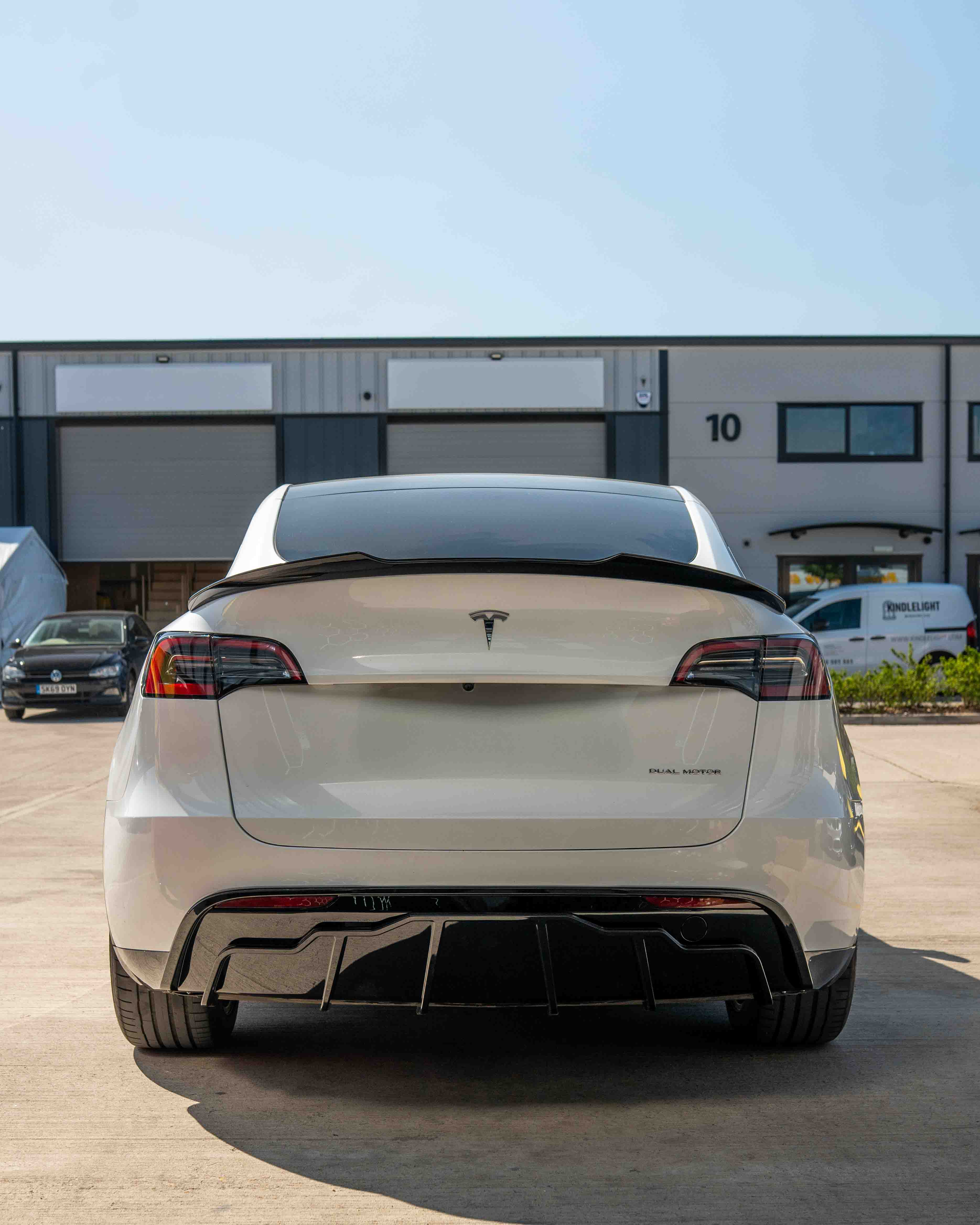 Full gloss black car kit for Tesla Model Y MK1 2020-2025 by CT Carbon, shown on a sleek vehicle with reflections.