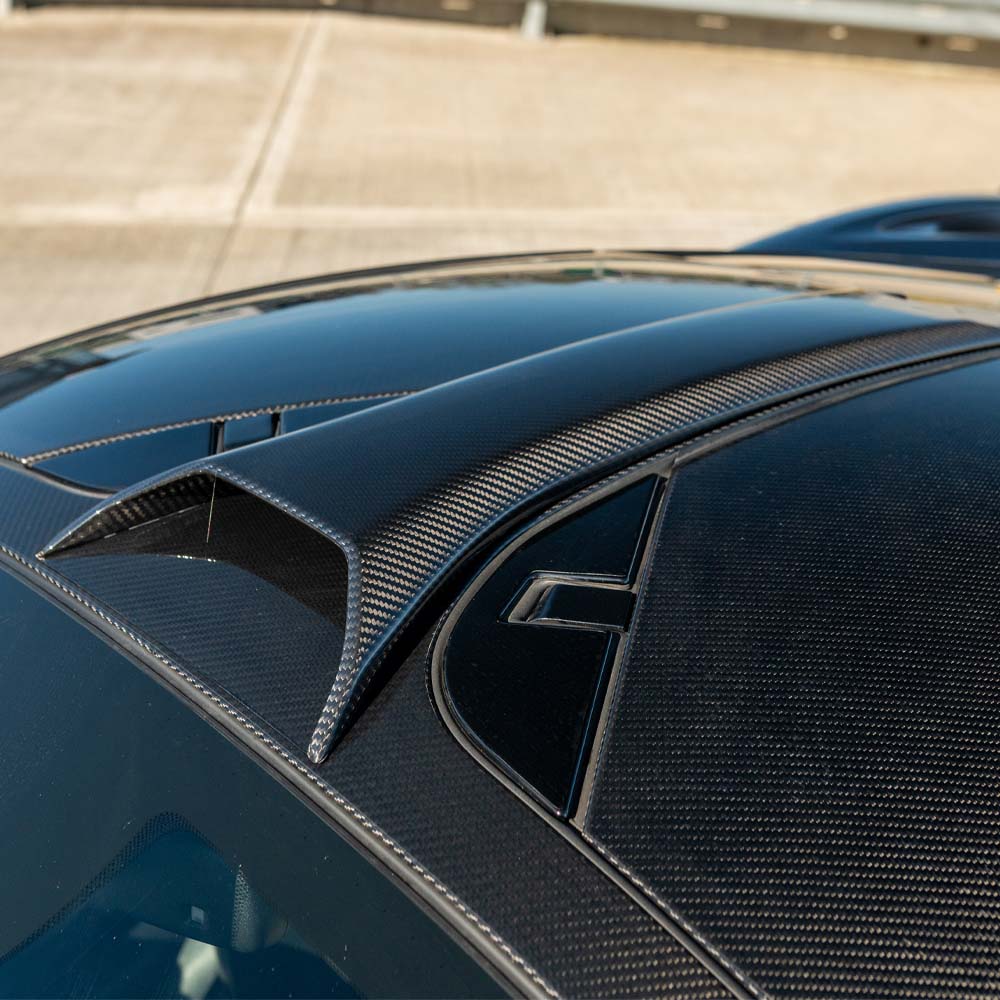 Carbon fiber roof scoop for McLaren 720S by CT Design, showcasing sleek, aerodynamic design and textured carbon fiber surface.