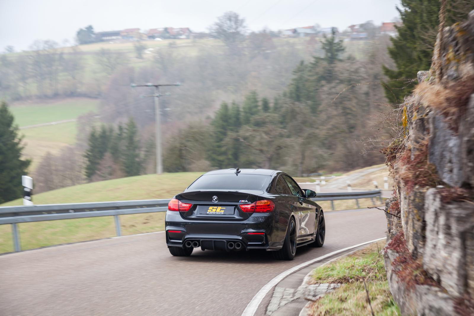 ST Suspension coilovers for BMW F80 M3 and F82 M4 with adjustable damping and top mounts, installed on a blue BMW M4 coupe.