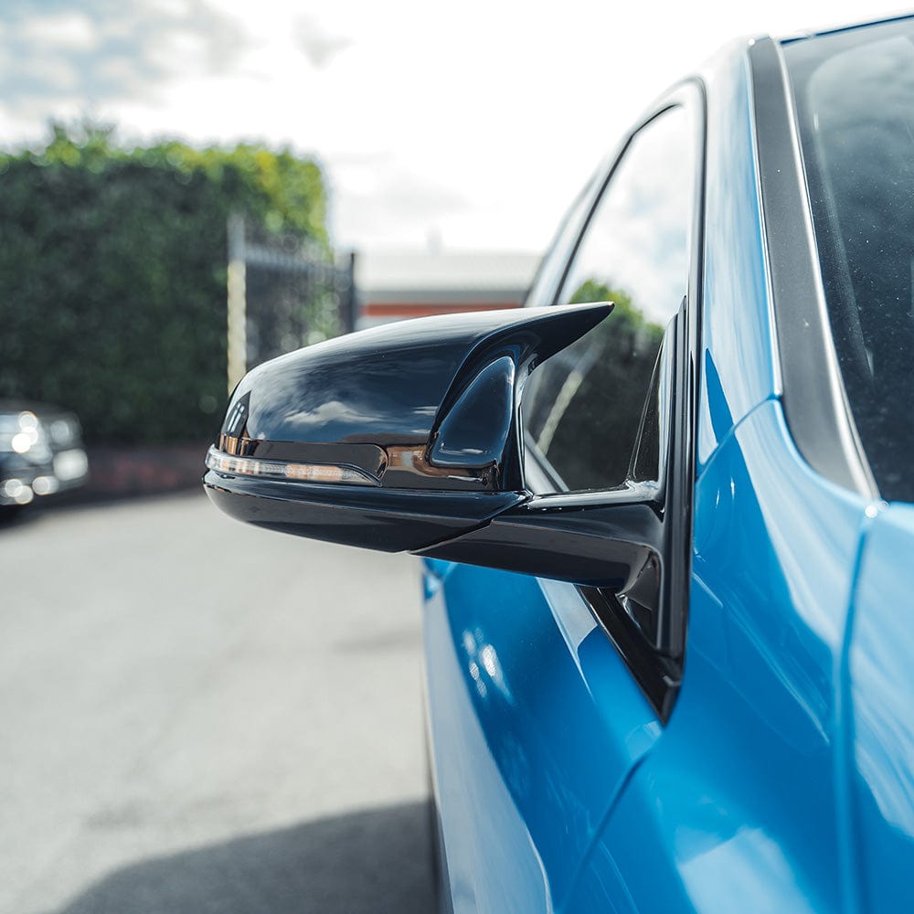 Gloss black replacement mirror covers for BMW F40 and F44 1 and 2 Series by CT Carbon, shown on vehicle side mirrors.