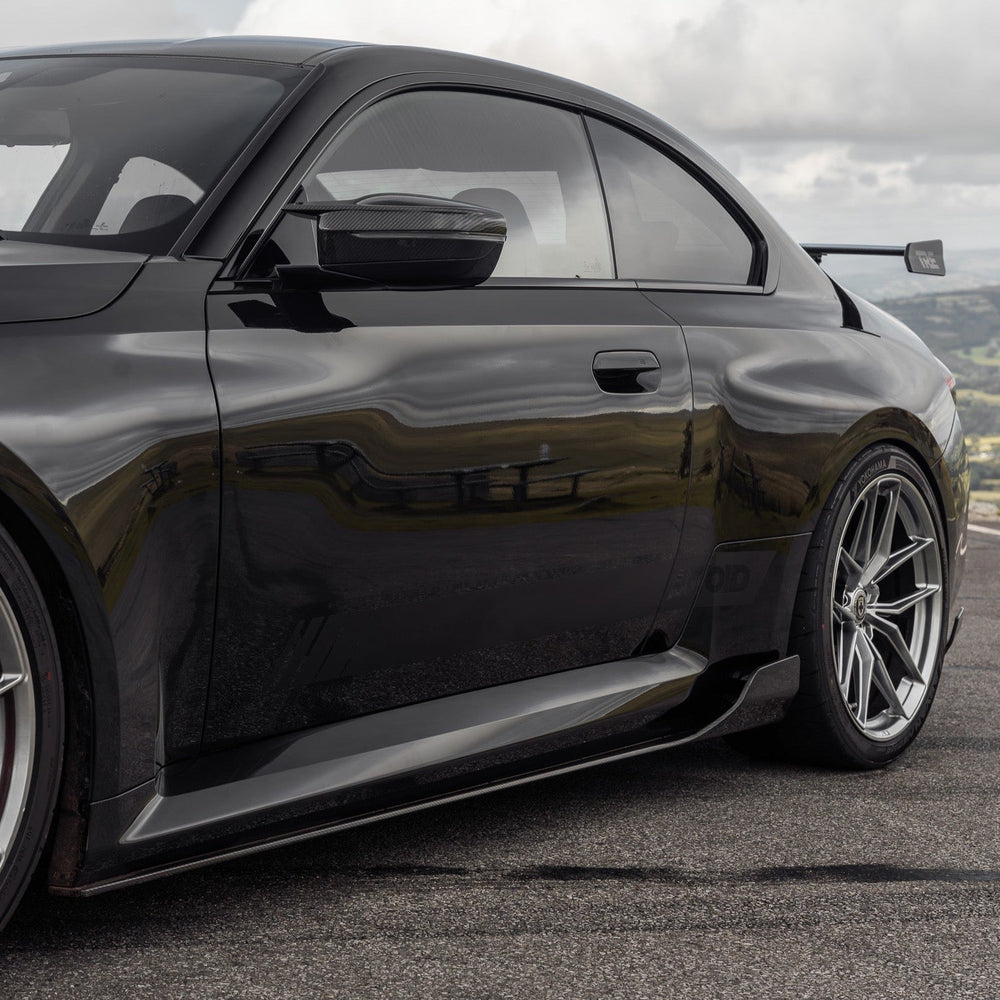 BMW G87 M2 TREVORA TR87 pre-preg carbon fibre side skirts installed on vehicle, showcasing sleek, lightweight aerodynamic design.