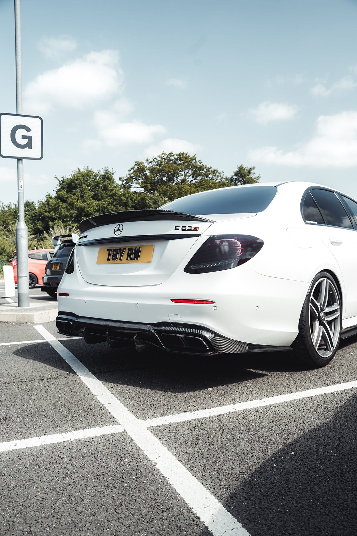 Carbon fiber diffuser for Mercedes E63 W213 2018-2020 pre-facelift by CT Carbon, showcasing sleek, textured finish on the vehicle's rear.