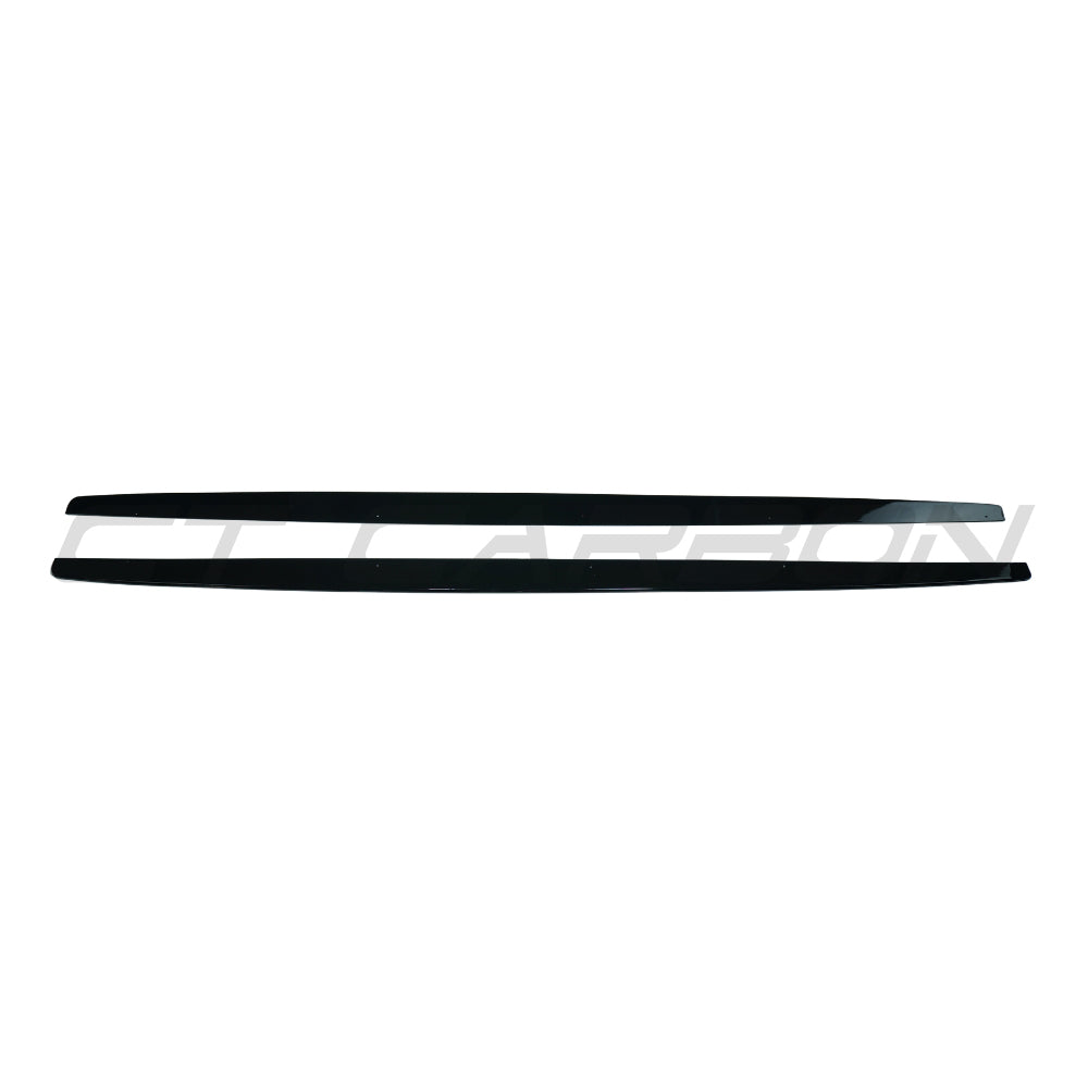 Gloss black BMW 1 Series E82/E83/E87/E88 side skirts by CT Carbon, showcasing sleek aerodynamic design on a silver car.