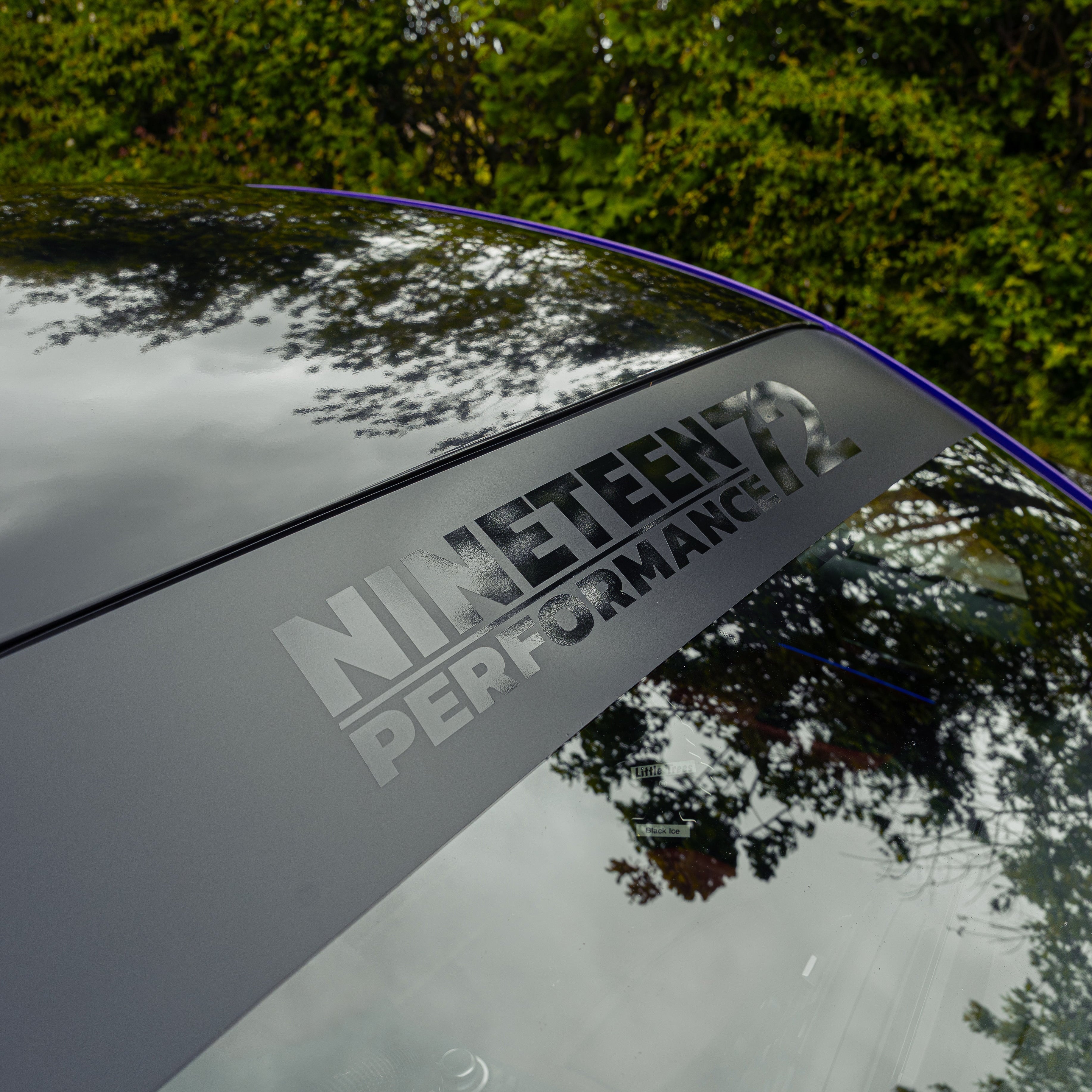 Nineteen72 Performance matte sunstrip with gloss black logo on a car windshield for enhanced style and sun protection.