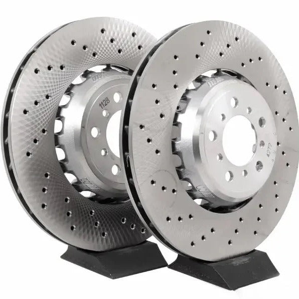 Two metallic brake rotors on a stand against a white background