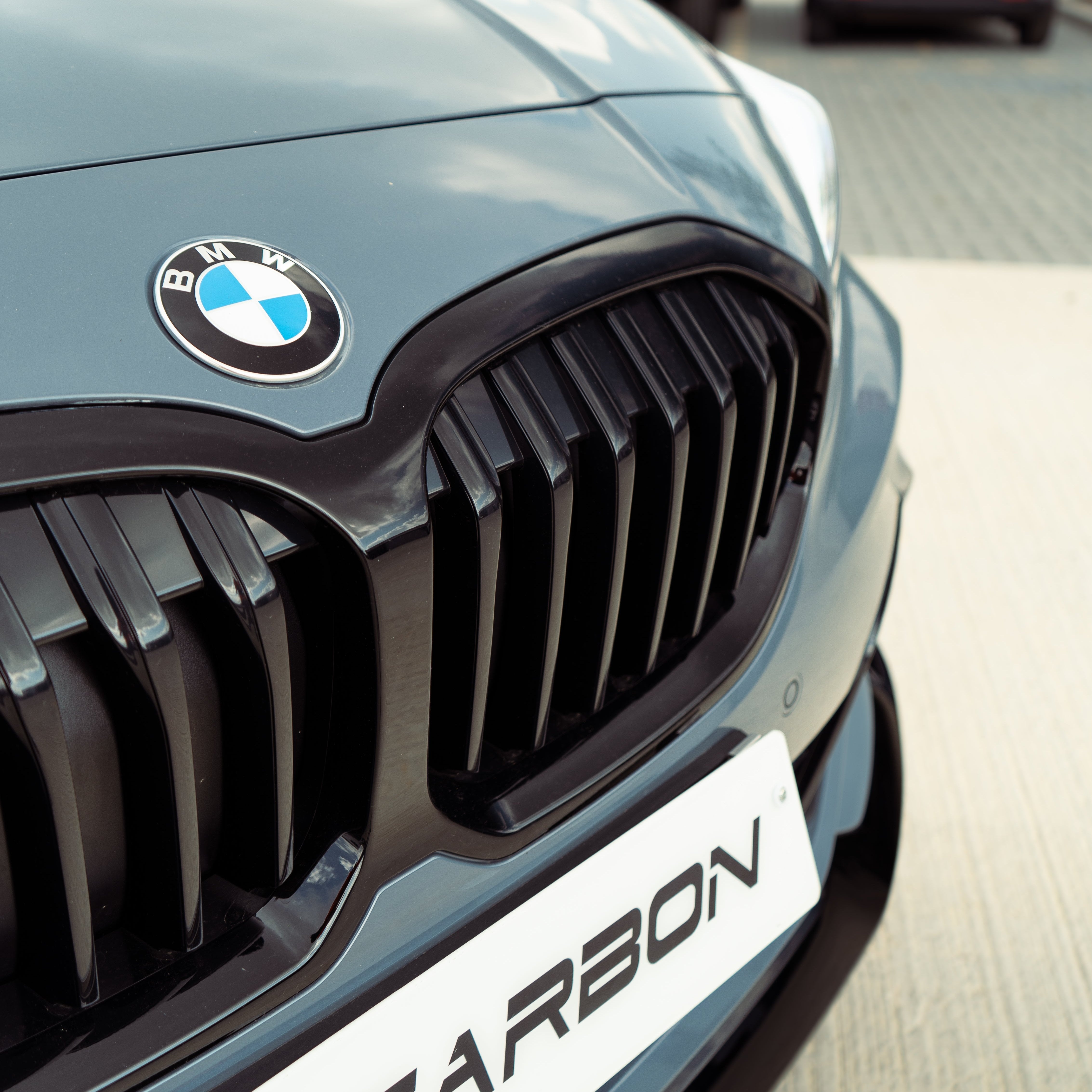 BMW F40 1 Series gloss black single slat grille by CT Carbon, showcasing the sleek, shiny grille design on a black background.