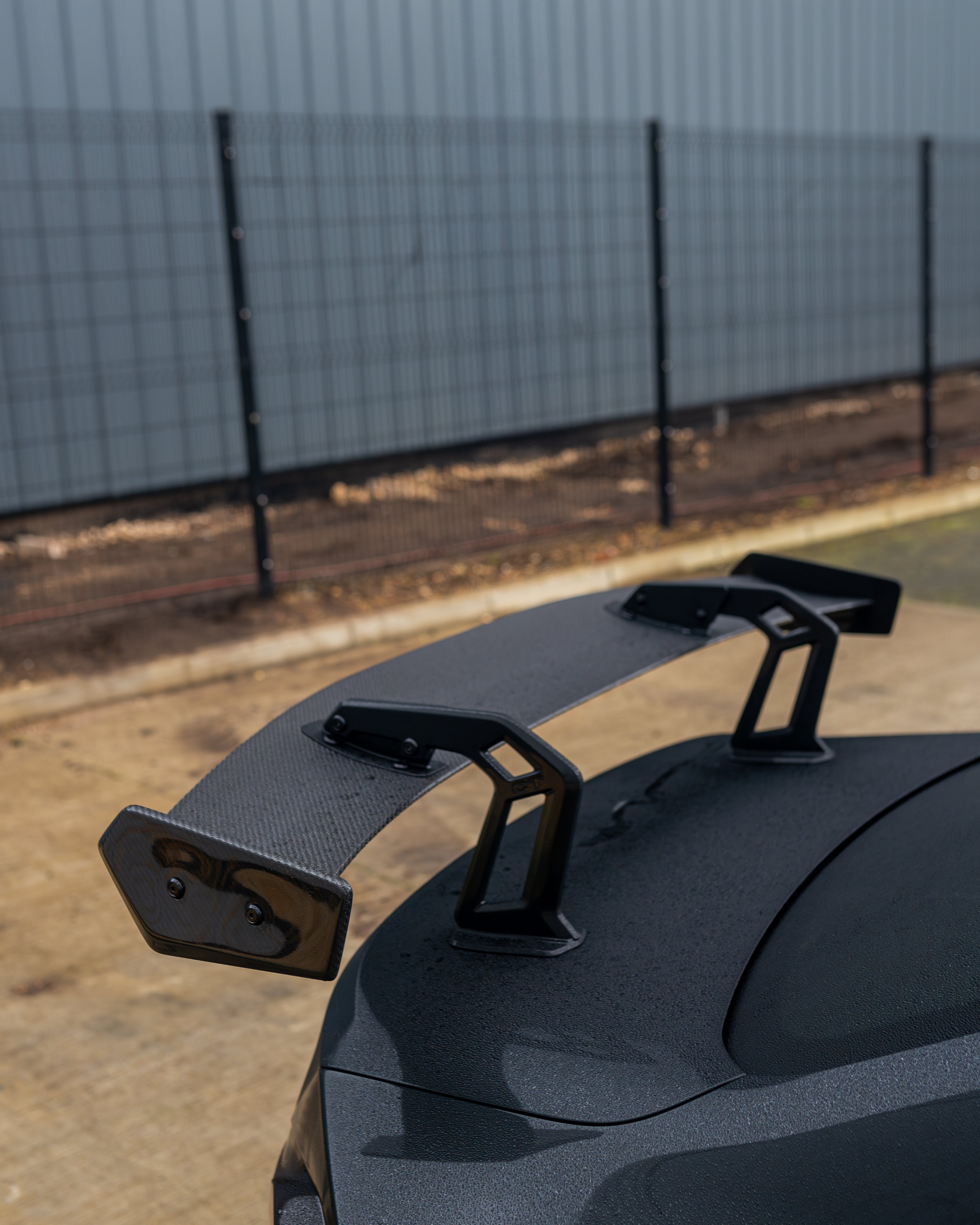 BMW G87 M2 and G42 2 Series carbon fibre swan neck wing spoiler by CT Design, shown on a sleek sports car.