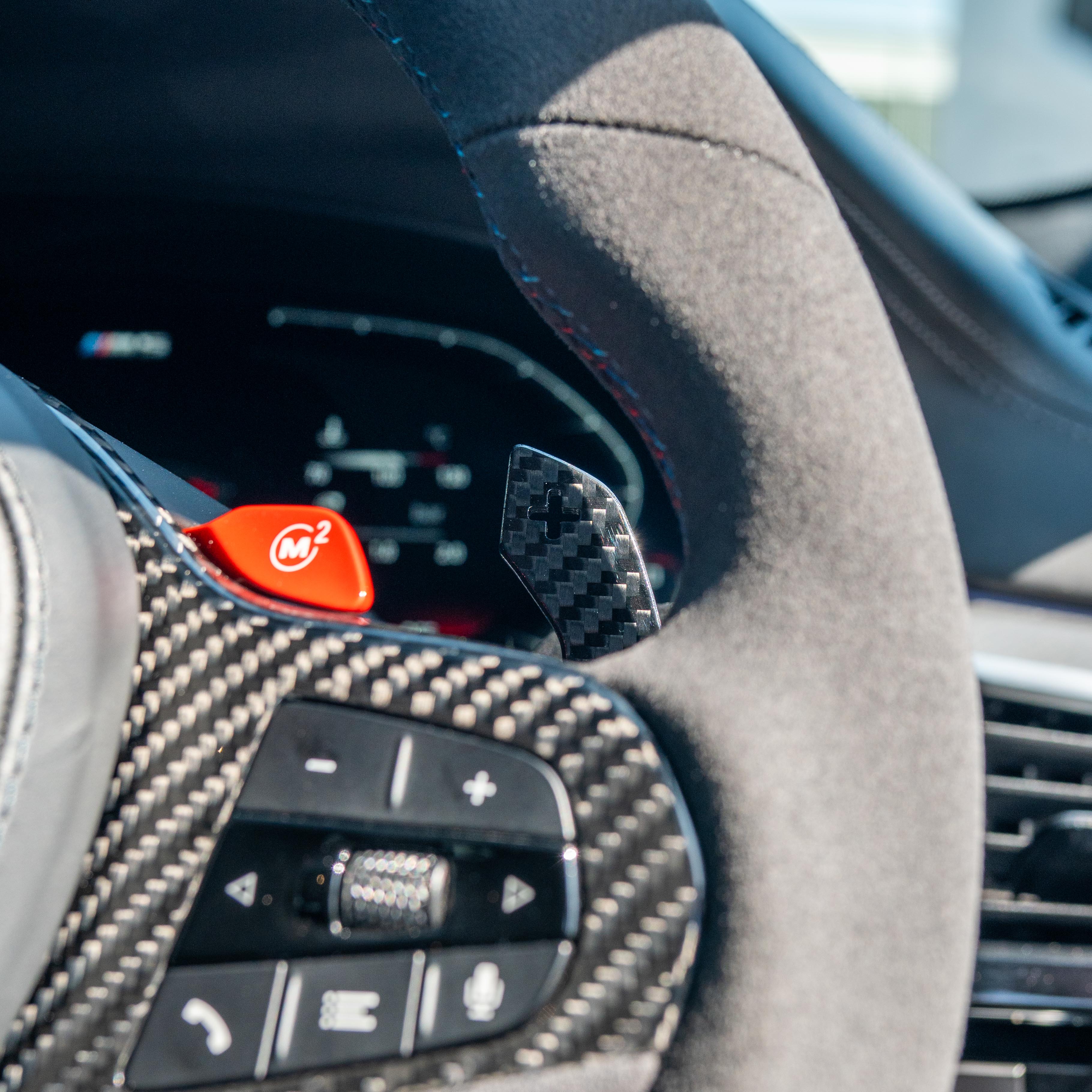 BMW Gxx carbon fiber magnetic shifter paddles by CT Carbon, showing sleek black carbon fiber surface with mounting details.