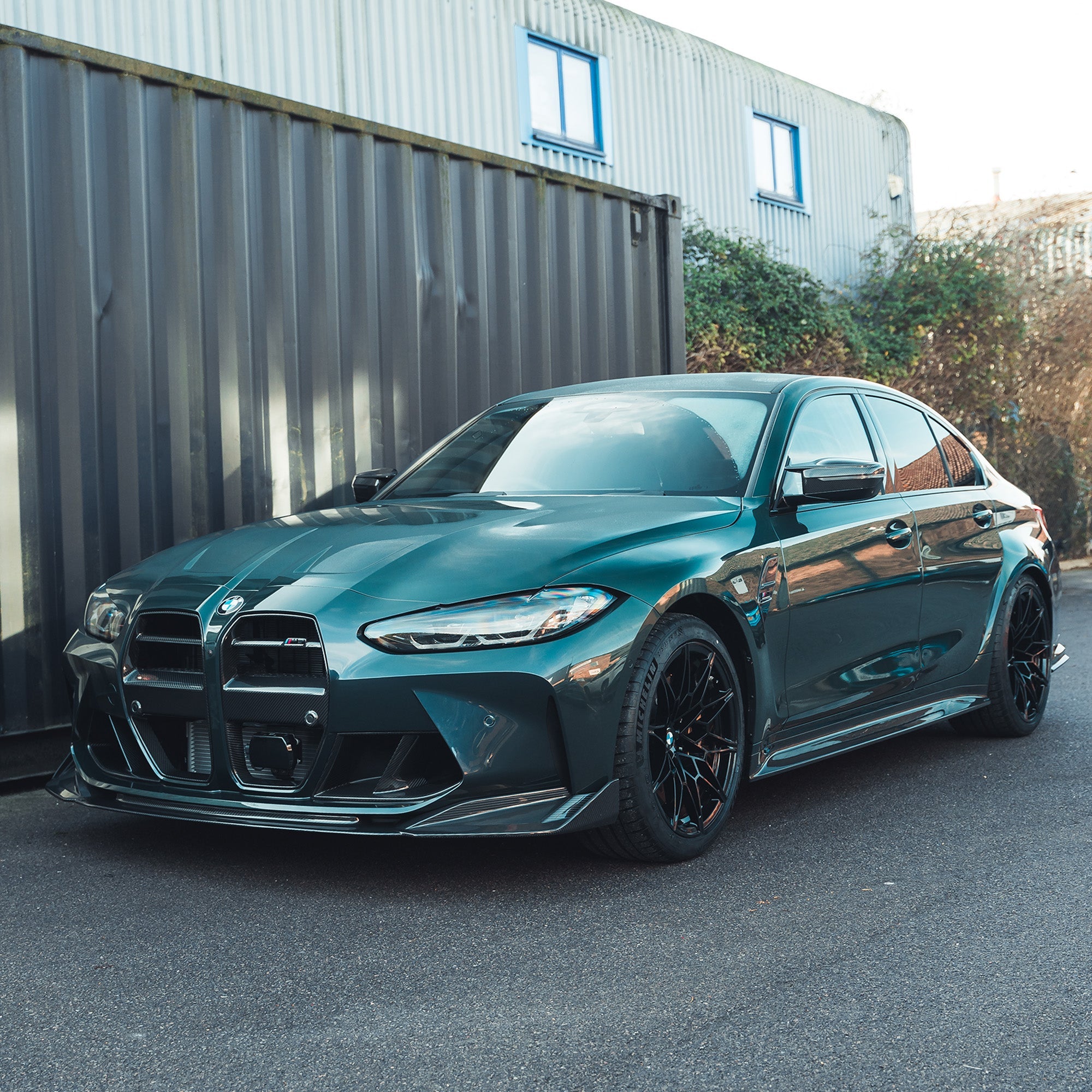 BMW M3 G80/G81 carbon fiber side skirt replacement by CT Carbon, showing sleek, textured carbon fiber side skirts installed on the vehicle.