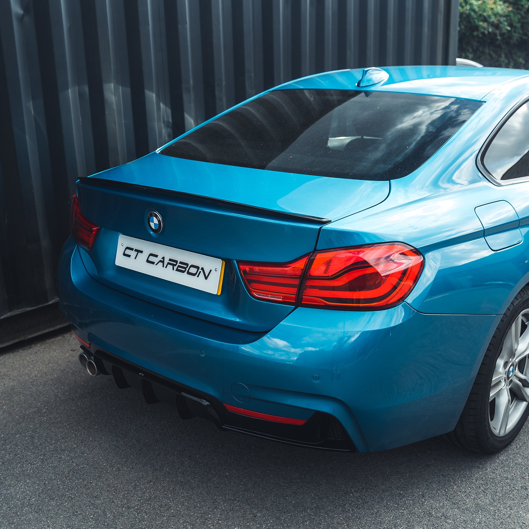 BMW 4 Series F32 2013-2020 gloss black full kit with twin exhaust by CT Carbon, shown on a blue BMW 4 Series vehicle.