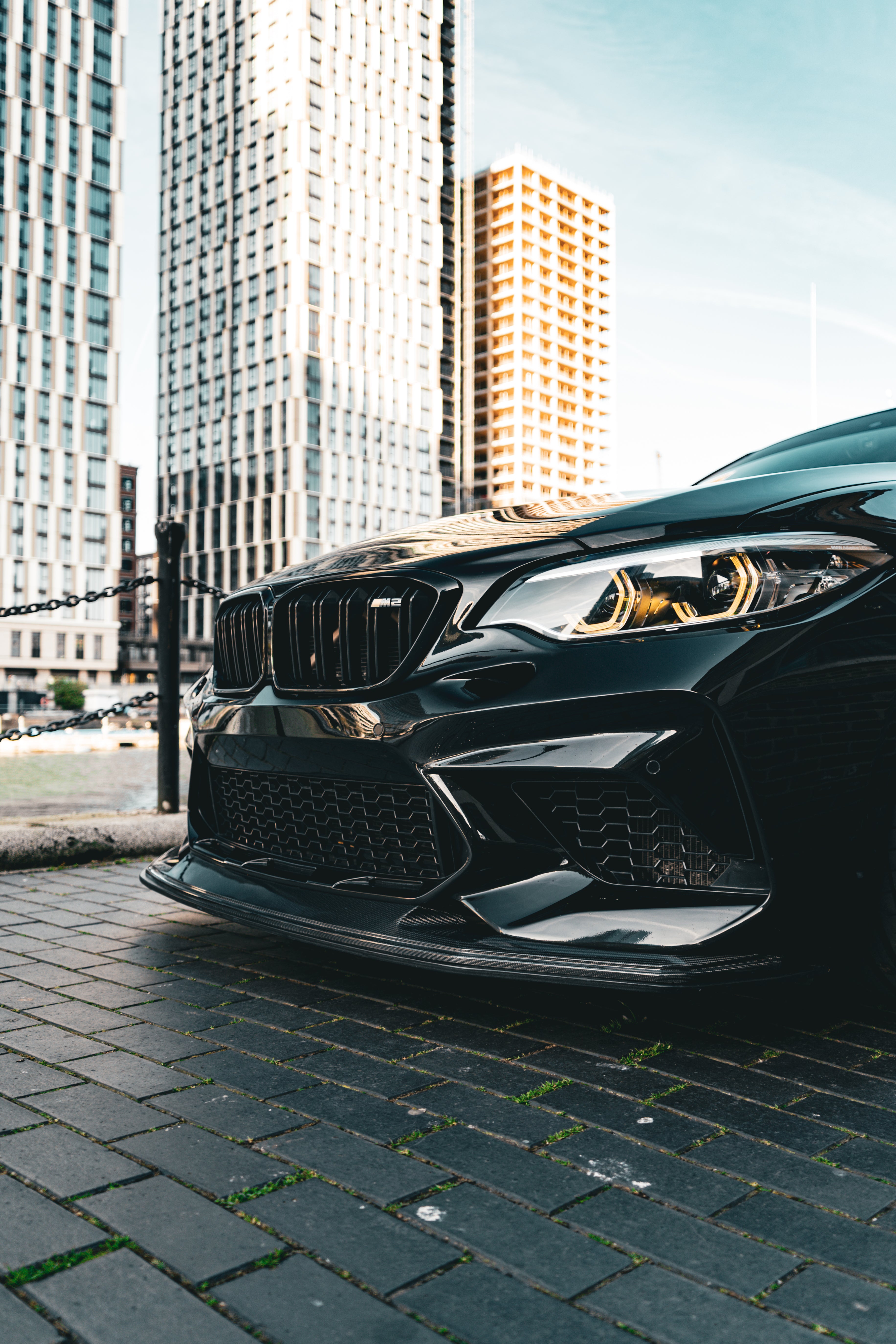 Black BMW car parked on a city street with tall buildings in the background