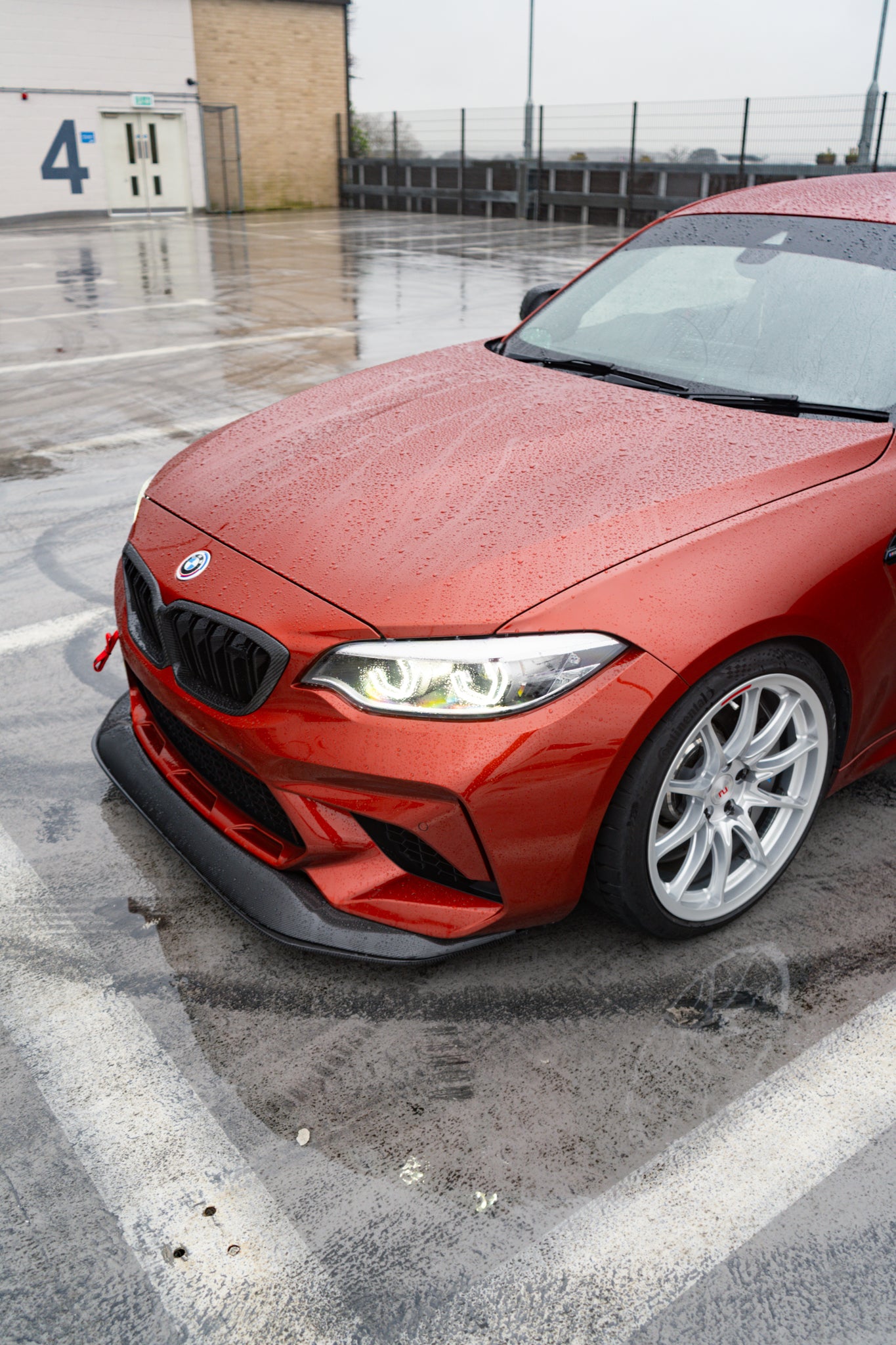 Ridgeline Motorsport carbon fibre GTS front splitter for BMW M2 Competition F87, shown installed on the vehicle's front bumper.