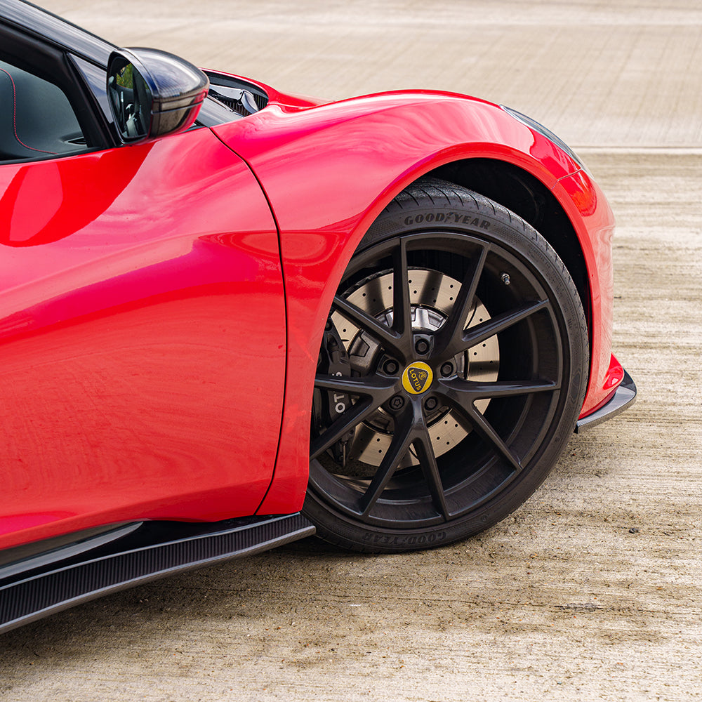 Red Lotus Emira car with CT Carbon fiber side skirts installed, showcasing sleek, aerodynamic design on a sporty vehicle.