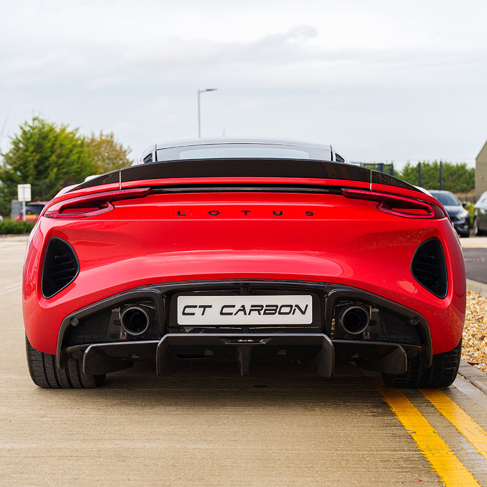 Red Lotus Emira CT Carbon fiber rear diffuser installed, showcasing sleek design and textured carbon fiber surface.