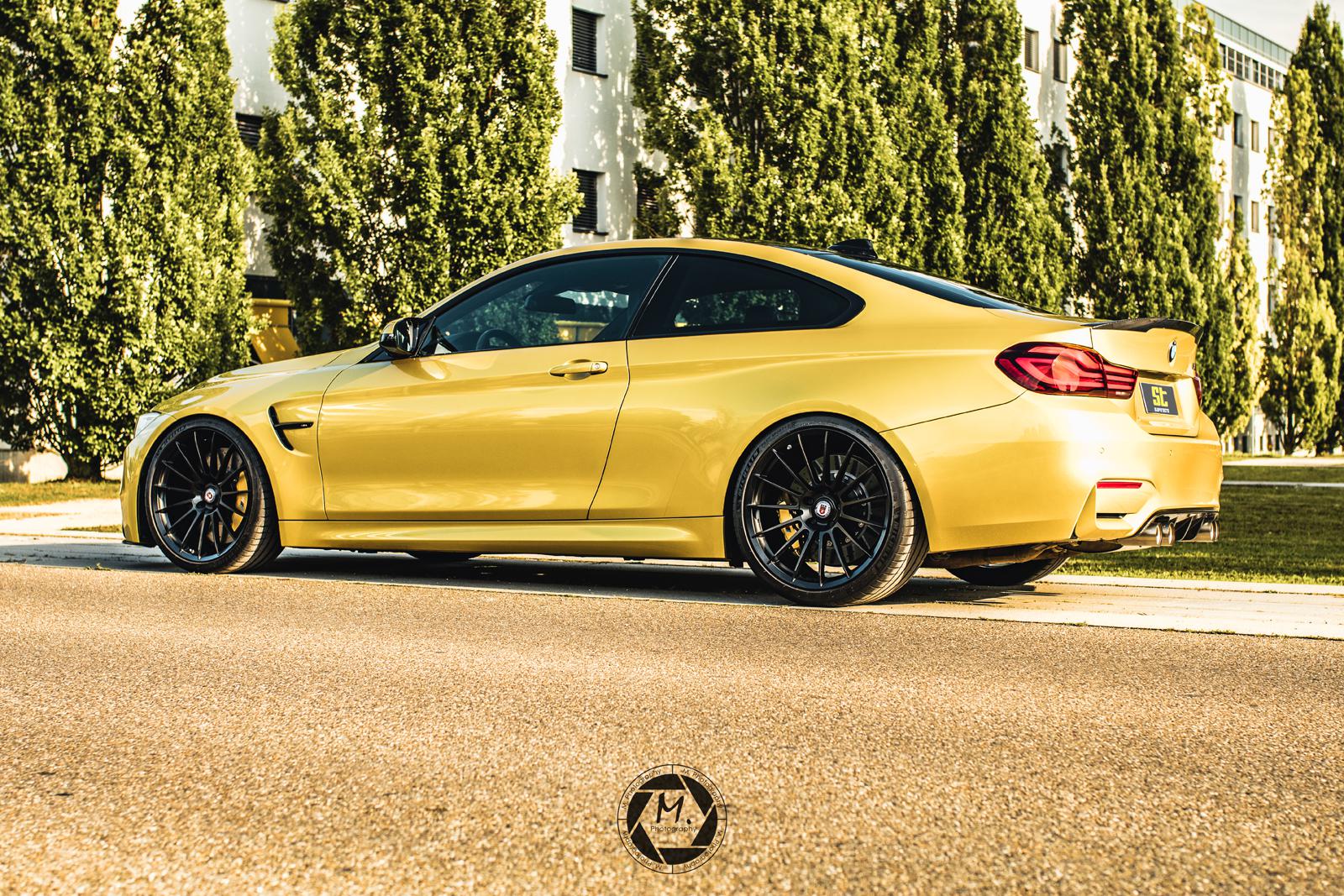 Gold ST Suspension coilovers for BMW F80 M3 and F82 M4 coupe with adjustable damping and top mounts, installed on vehicle.