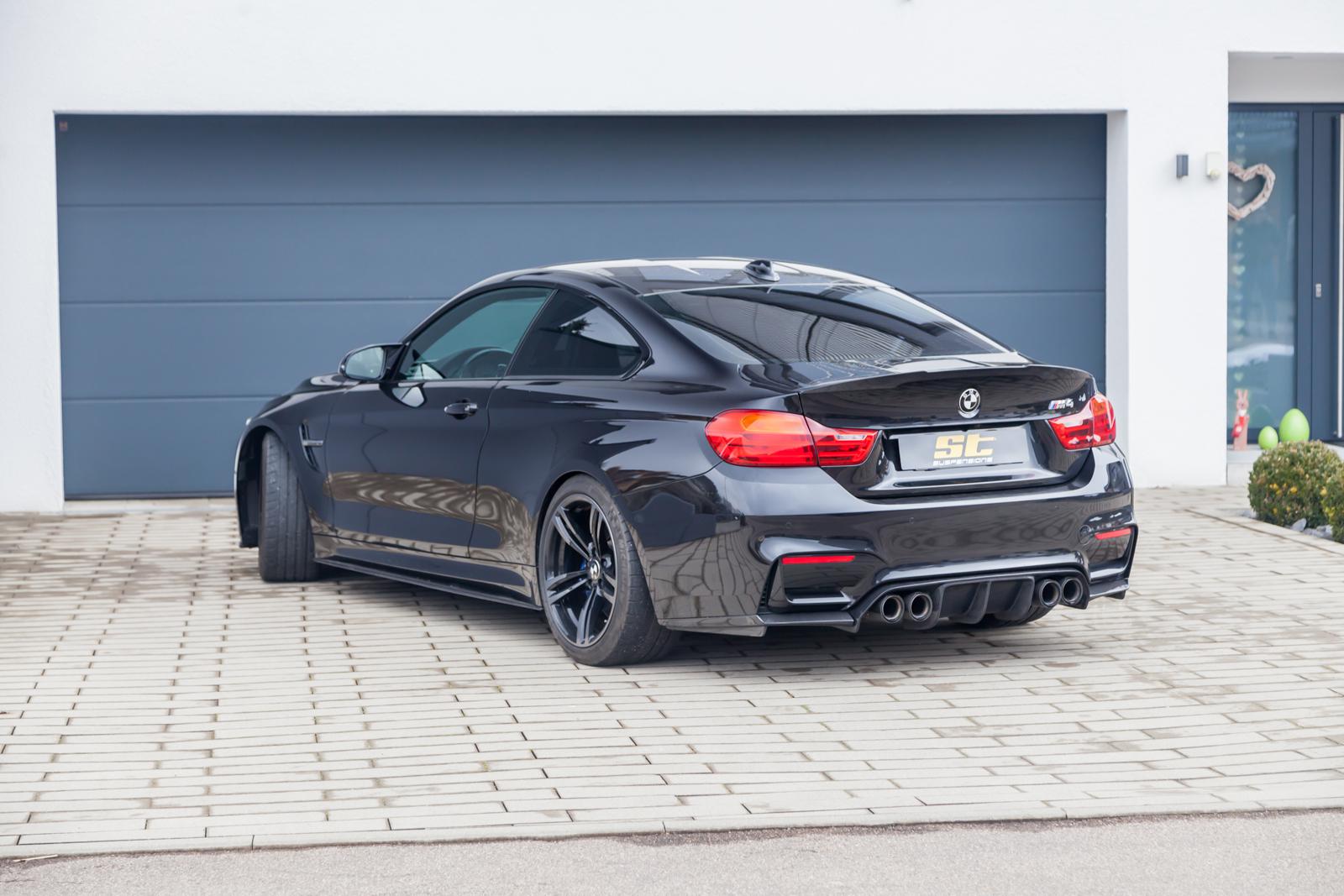 ST Suspension coilovers for BMW F80 M3, F82 M4, F83 M4 with adjustable damping and top mounts, shown on a black BMW M4 coupe.